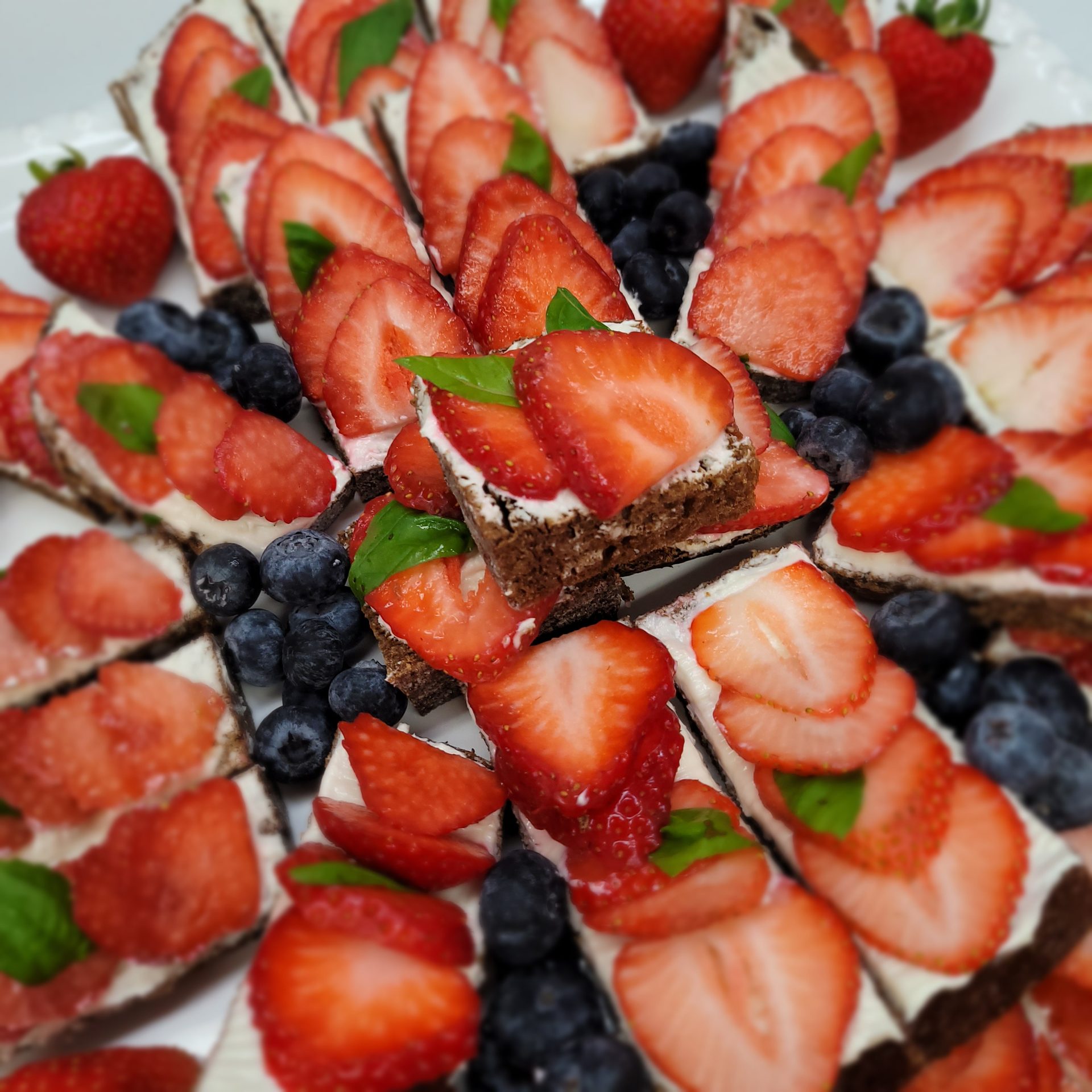 Strawberry and blueberry cream dessert bars with fresh basil